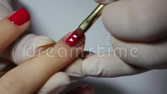 特写美甲师应用红色凝胶指甲油美容美发沙龙做美甲的女人视频的预览图
