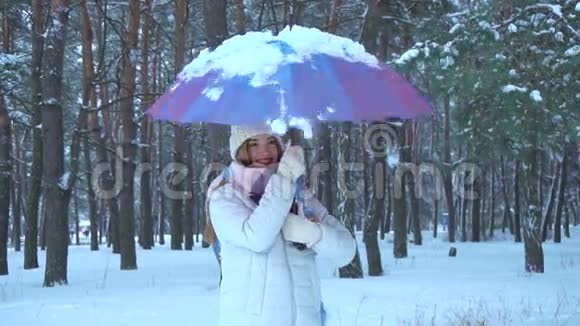 女孩站在树林里转动落在雪中的伞视频的预览图