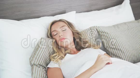 一个可爱的金发女郎正睡在一张轻床上清晨视频的预览图