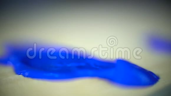 宏观拍摄如从白色管挤压蓝色油漆和涂抹白色刷子在木制调色板宏观拍摄视频的预览图