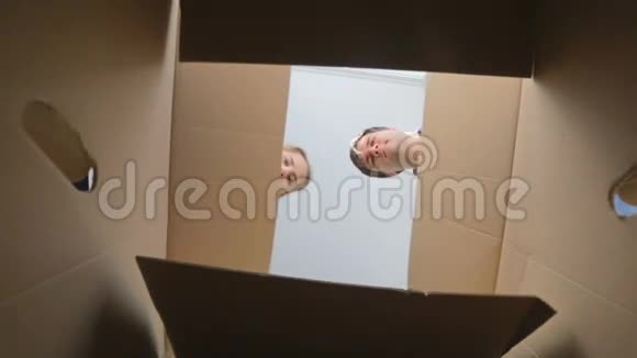 从纸板箱的内部看年轻的微笑夫妇打开它视频的预览图