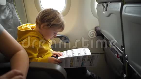 飞机上一个穿黄色夹克的男孩在读安全说明书时慢镜头视频的预览图