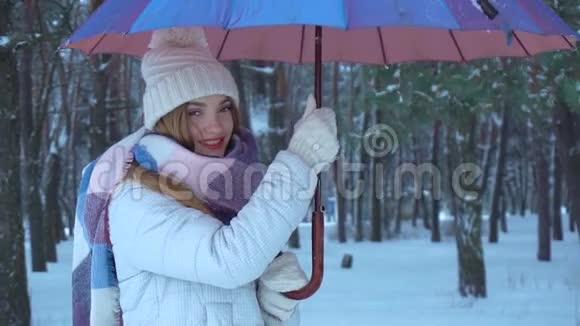 女孩站在伞下扭动它在雪地上倾泻视频的预览图