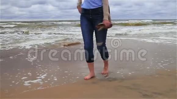 一个女孩光着脚沿着海岸走视频的预览图