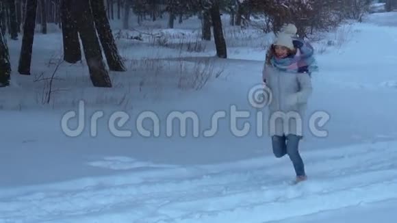 小女孩在树林里的雪地里奔跑微笑着视频的预览图