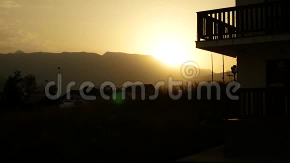 日落山中日出黎明4k背景下群山中房子的轮廓视频的预览图