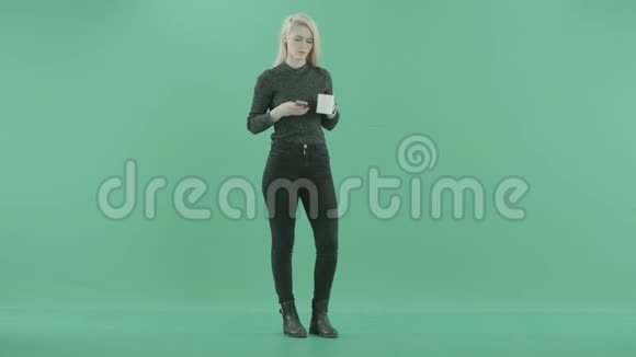女人拿着一杯茶站在电话里视频的预览图