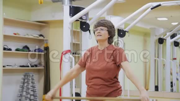 老年妇女伸展身体在健身室用棍子做理疗健康体操积极主动视频的预览图