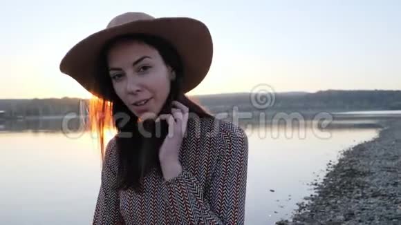 可爱的小女孩戴着帽子在湖边对着镜头微笑视频的预览图