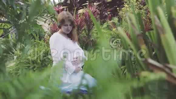 快乐的孕妇坐在膝盖上放松和享受大自然中的生活视频的预览图