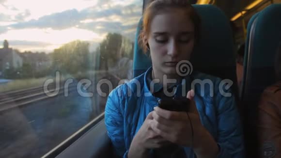 年轻的黑发美女使用智能手机坐在火车的窗户附近视频的预览图