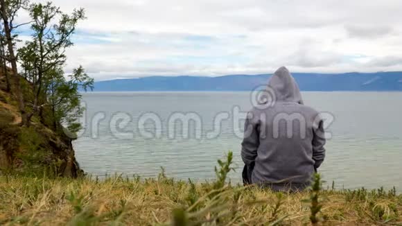 一个人在多云的天气里坐在海滨沉思着4K时间流逝视频的预览图