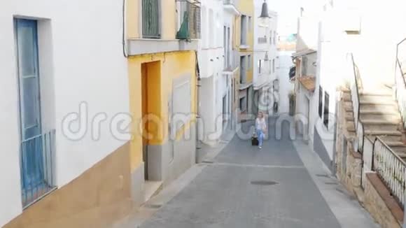带着旅行袋的游客沿着西班牙老欧洲城市的狭窄街道走去视频的预览图