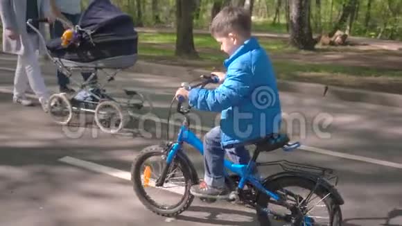 城市公园里骑蓝色自行车的小男孩视频的预览图