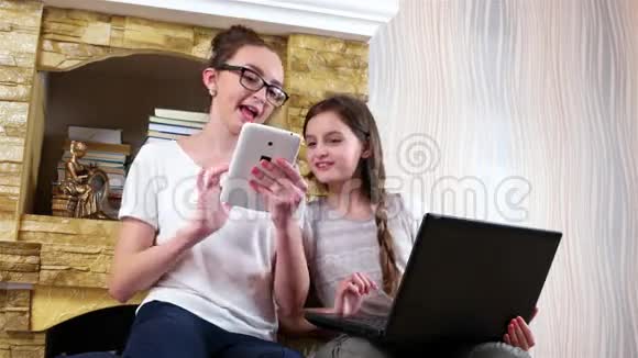 朋友们在家里社交在笔记本电脑和平板电脑上玩游戏女孩们坐在一起视频的预览图