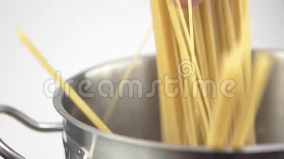 一个厨师把一个意大利面放在白色背景的钢锅里视频的预览图