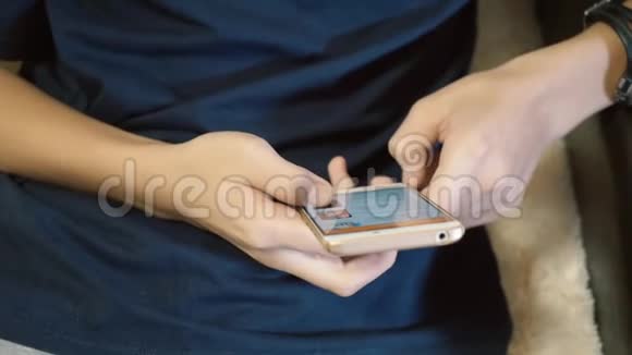 一个十几岁的孩子看着他智能手机上的新闻双手握住手机特写视频的预览图