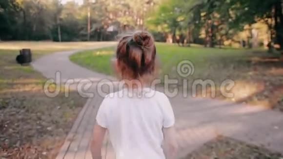 小女孩在公园的路上散步一束美丽的头发在阳光下闪闪发光慢影后景视频的预览图