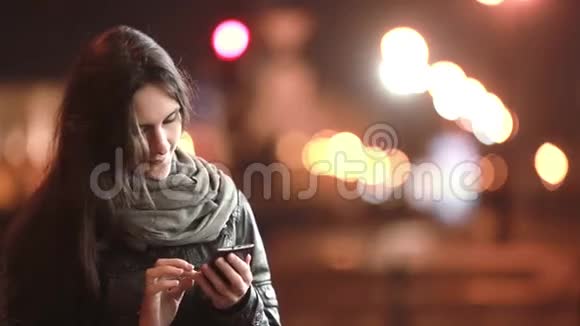 漂亮的年轻女人微笑着接电话晚上打电话在寒冷的天气里街上的女士视频的预览图