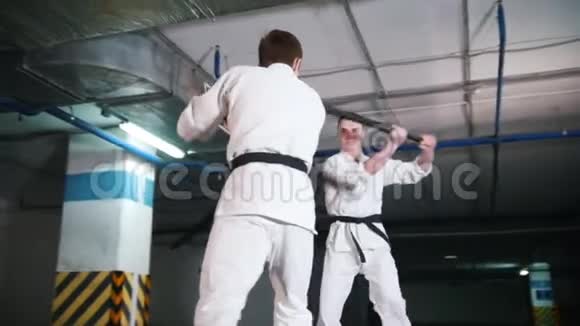 两个穿和服的男人在停车场训练剑道剑战视频的预览图