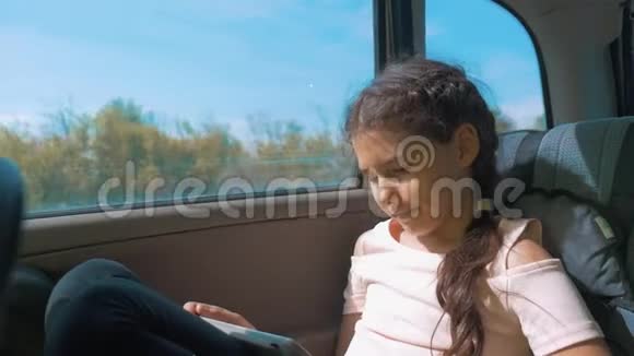 小女孩坐在车里带着平板电脑互联网社交媒体去旅行汽车概念旅行运输女孩视频的预览图