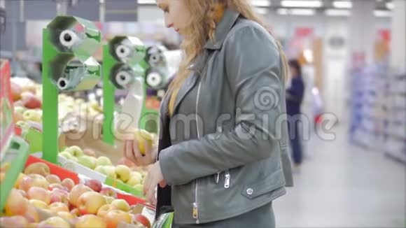 漂亮的年轻漂亮的红发女人在市场上在超市里买食物水果苹果女孩选择视频的预览图