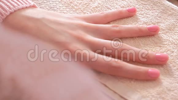 女人把第二层粉红色的紫胶涂在指甲上特写双手视频的预览图