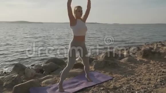 那个美丽的运动女子在海滨做早操海滩和日出的背景视频的预览图