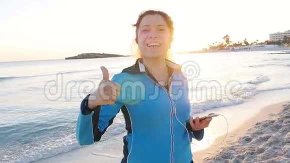 微笑女性健身节目在海滩上竖起大拇指视频的预览图
