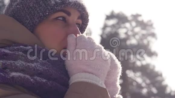 一位在户外散步的年轻女子在冬天的公园里散步时她用手臂呼吸以保暖视频的预览图