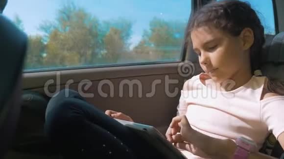 小女孩坐在车里带着平板电脑互联网社交媒体去旅行汽车概念旅行运动运输视频的预览图