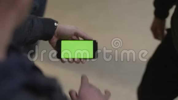 年轻的男性手举着绿色触摸屏的现代智能手机男子手拿手机视频的预览图