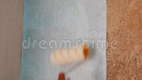一张蓝色墙纸的女士手纸用一种特殊的施工滚筒粘在墙上视频的预览图