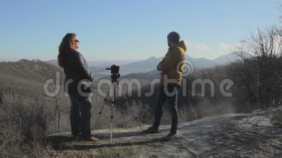 男人和女人用三脚架上的摄像机拍摄风景视频的预览图