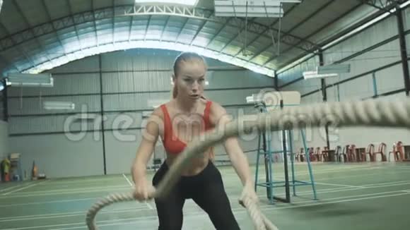 一个有魅力的年轻和运动的女孩在健身房里使用训练绳视频的预览图