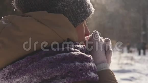 一位在户外散步的年轻女子在冬天的公园里散步时她用手臂呼吸以保暖视频的预览图