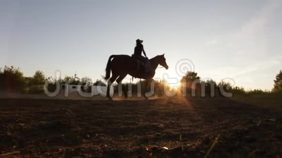 剪影拍摄了一位骑马的人脸上带着尘土夕阳在太阳面前慢镜头视频的预览图