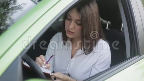 漂亮的年轻女人坐在她的车上为她的日记做笔记秋天的心情视频的预览图