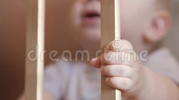 可爱的金发美女在婴儿床上玩耍集中注意力手抓住栅栏视频的预览图