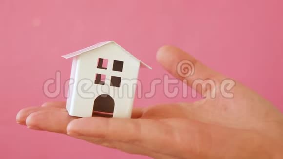 简单地设计女性手拿微型白色玩具屋孤立的粉红色粉彩五颜六色的时尚背景视频的预览图