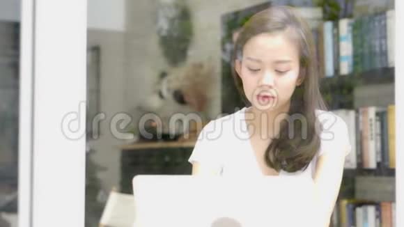 美丽的肖像亚洲年轻女子微笑着在网上工作快乐地坐在咖啡馆里视频的预览图