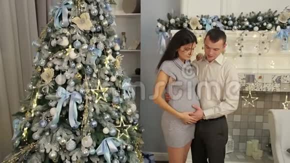 孕妇和她丈夫在圣诞树附近视频的预览图