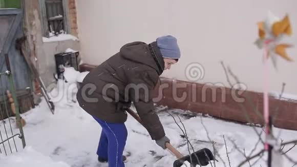一位老年妇女打扫房子附近的雪铲视频的预览图