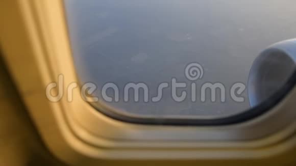 飞机机翼通过飞机窗口的视图日出时在云层上方飞行视频的预览图
