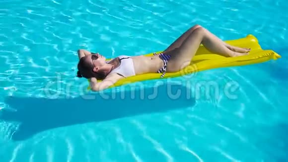 年轻女子在室外游泳池的空气床垫上放松视频的预览图