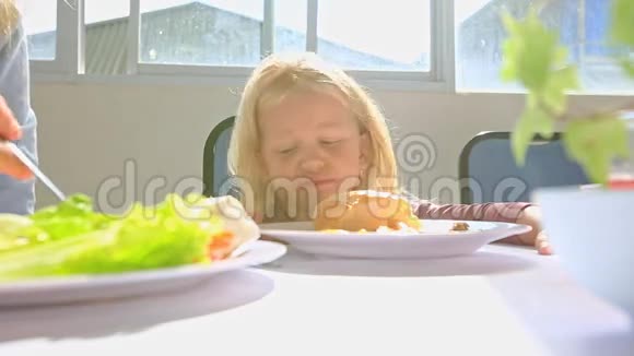 在餐桌旁的早餐移动餐盘上的小金发女孩讲座视频的预览图