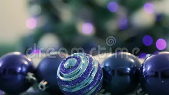 用蓝灯装饰的圣诞树前景中的圣诞球背景中一棵圣诞树模糊的图像视频的预览图