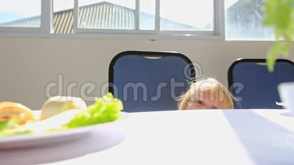 金发小女孩在餐桌上坐下妈妈给她理发视频的预览图