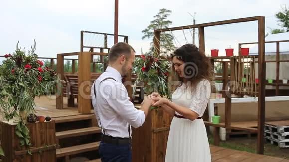 温柔美丽的新娘把结婚戒指戴在新郎手指上概念婚礼乡村化视频的预览图
