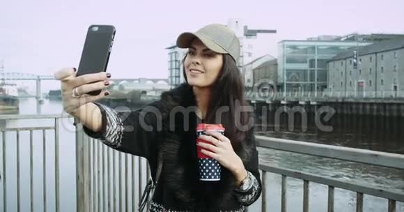 一个女孩在一个美妙的地方自拍喝杯咖啡一座桥一条河的背景4K视频的预览图